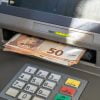 Wypłata z bankomatu za granicą - banknoty euro wystające z bankomatu